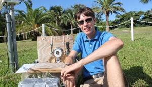 BIOS intern Shane Antonition sits next to a traditional shark oil barometer