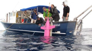 scientists deploy a glider off the side of a research vessel