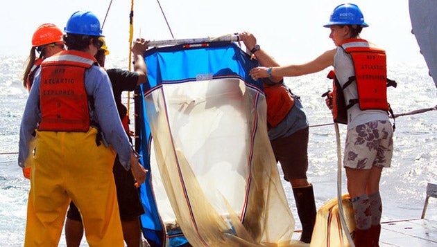 Scientists pull in a sampling net aboard a research vessel